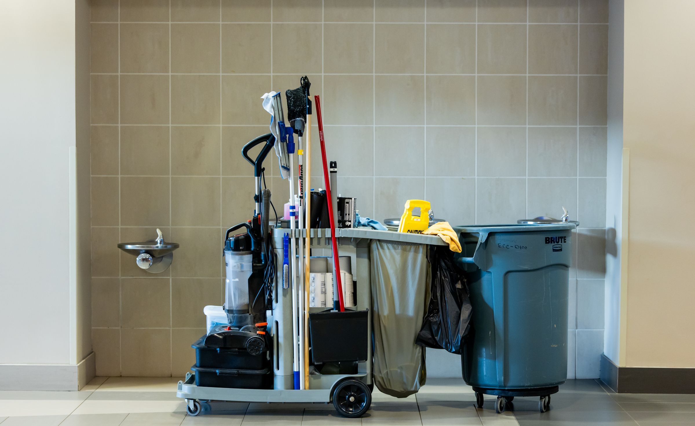 A janitorial cart stocked with cleaning tools inside an office building