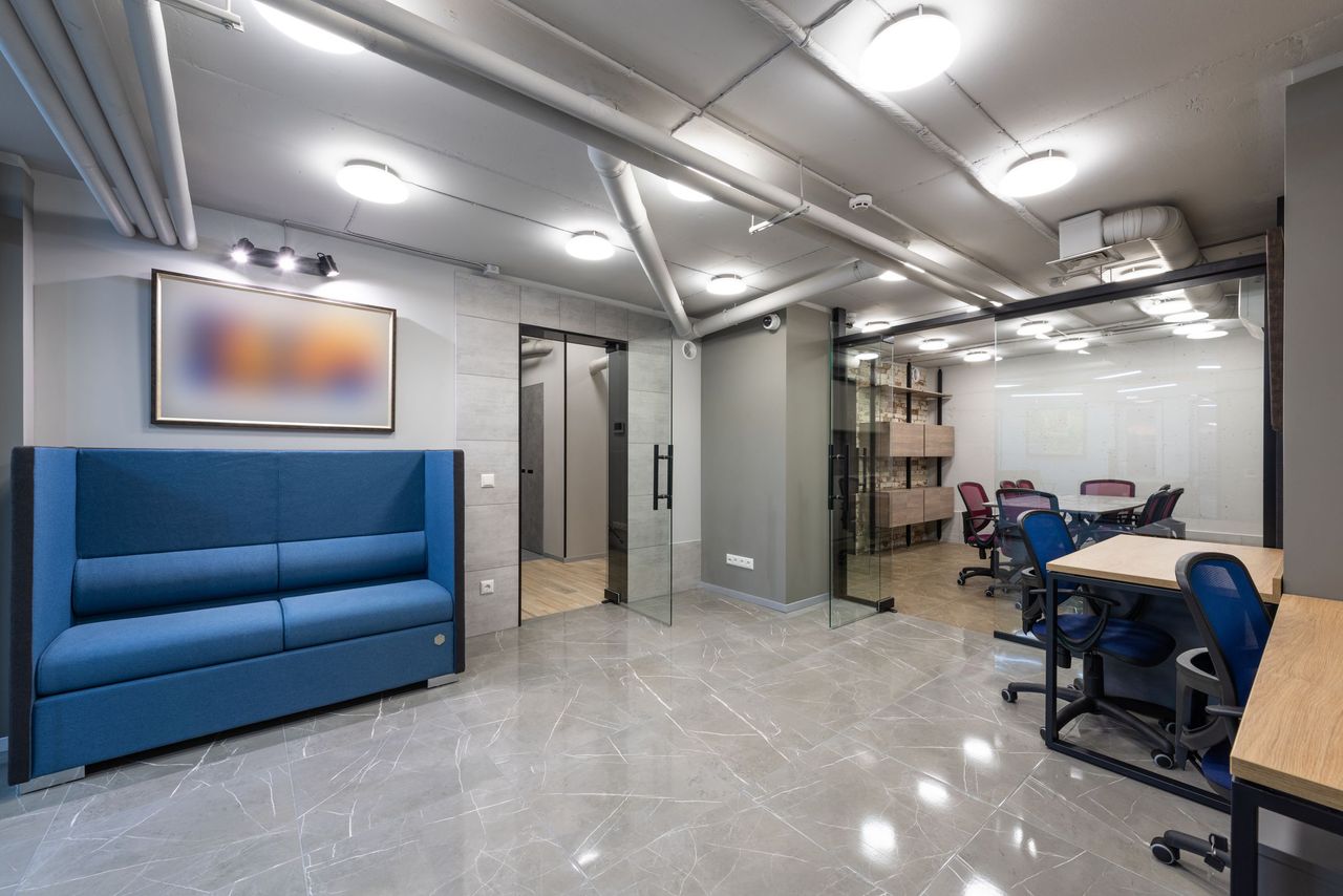 A newly finished office with blue seating, glass-walled rooms and glossy tile floors
