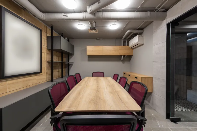 A conference room with a long wooden table, red mesh chairs and a glass door