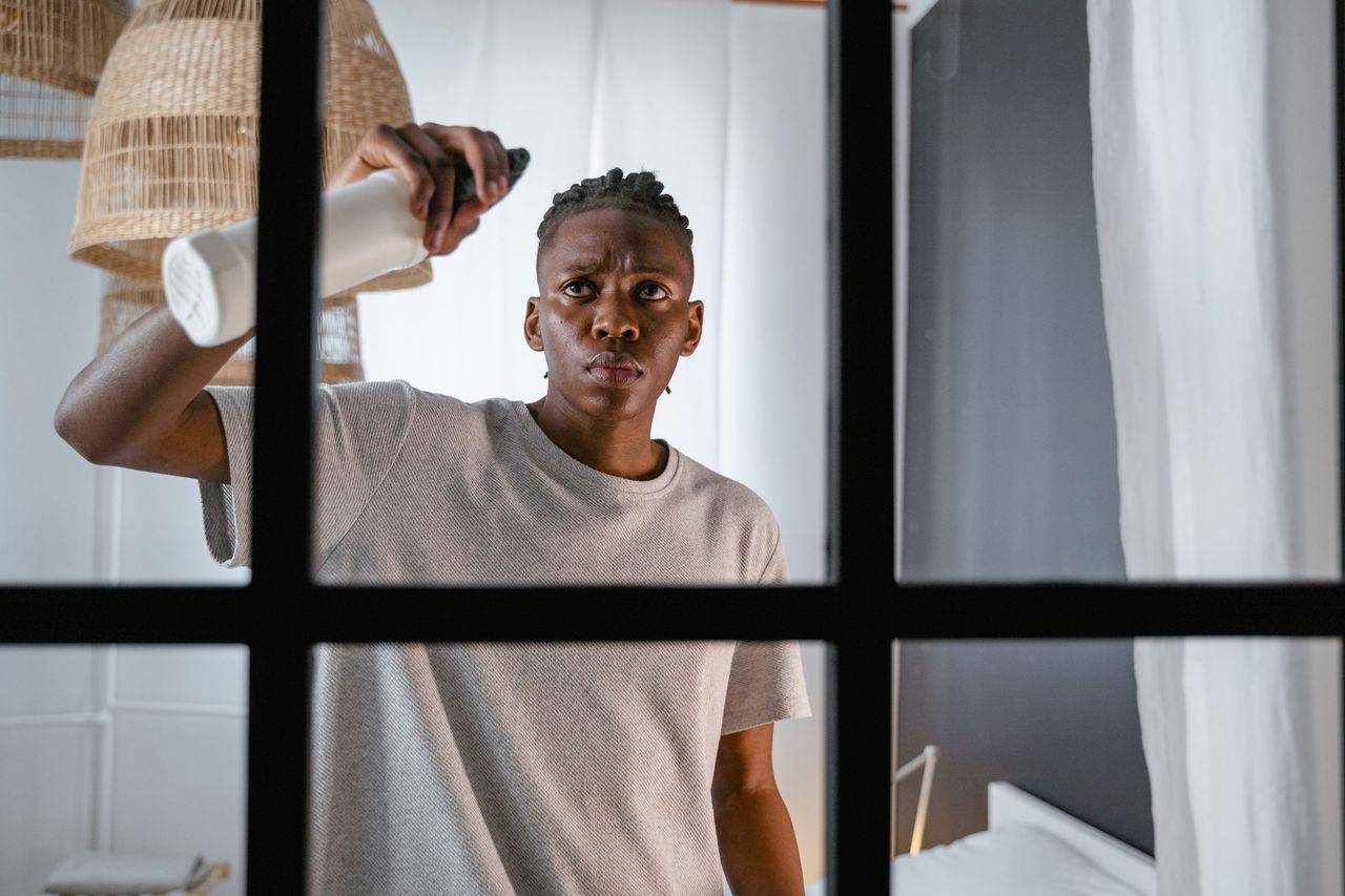 A man spraying and wiping the inside of a window pane