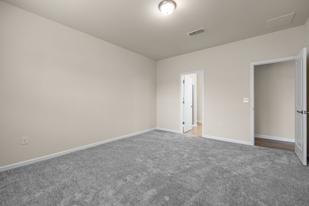 A freshly finished, empty bedroom with new gray carpet and white trim
